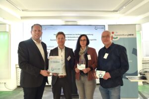 Marco Schmitz, Stiftungsratsvorsitzender der SozialstiftungNRW, überreicht einen Spendenbescheid an die Lebenshilfe Brakel für das Verbundvorhaben 'Assistive Technik im Wohnen in der Eingliederungshilfe'.