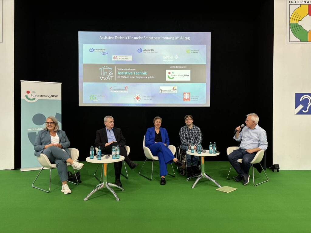 Podiumsdiskussion auf der Rehacare. Das Bild zeigt fünf sitzende Personen, die auf der Bühne der Rehacare diskutieren.